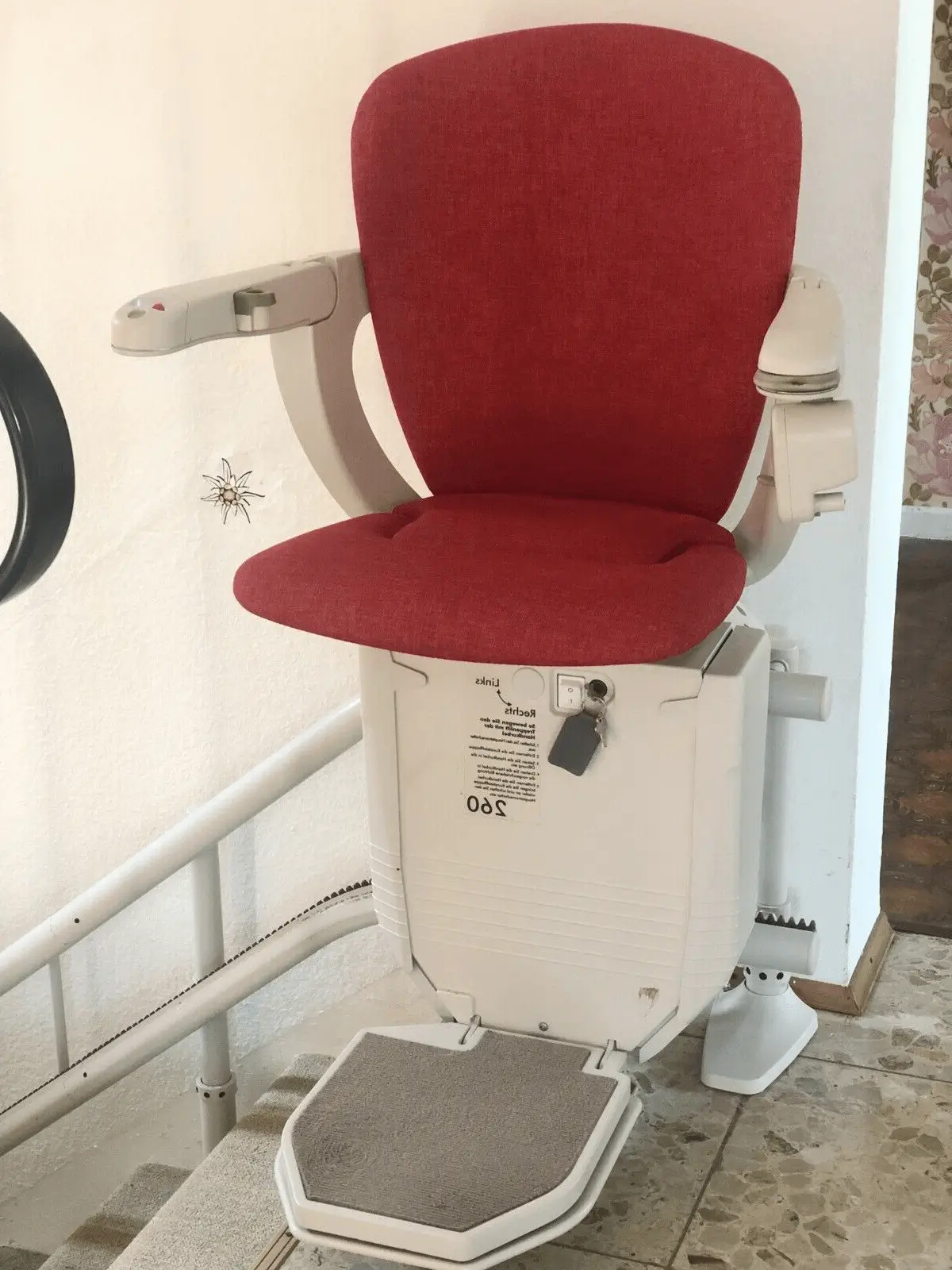 Red curved stairlift with manual one-way swivel seat on stone stairs in Shidler