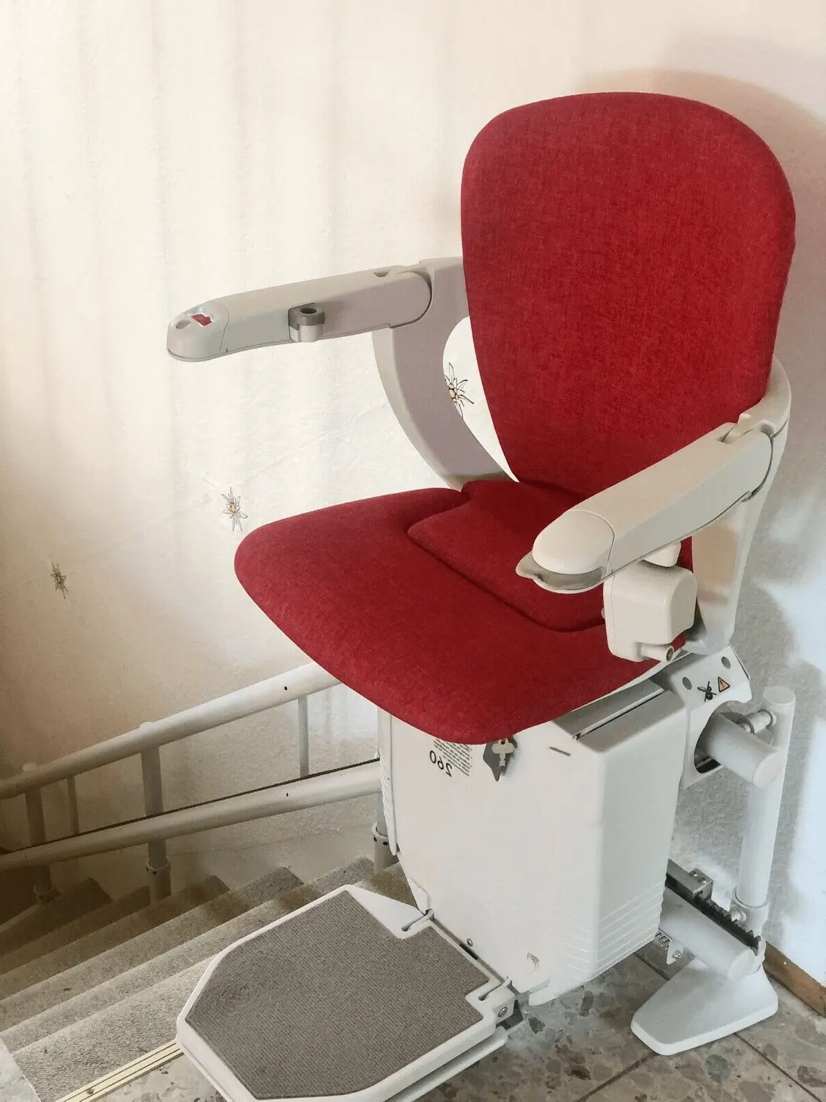 Curved stairlift showing electric folding footrest on indoor stone staircase in Shidler