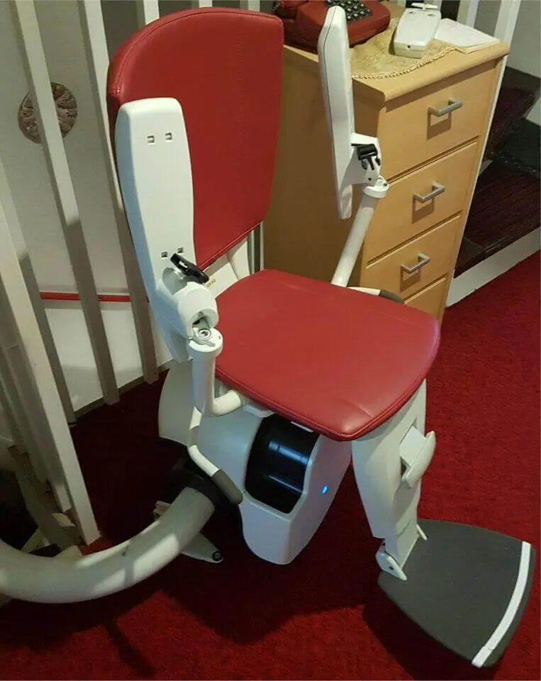 Angled profile view of a red-curved stairlift with single-rail track installed in a Shidler home.