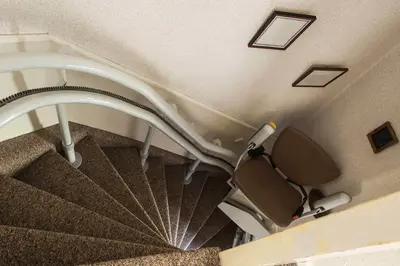 Downward angle of a brown-upholstered curved stairlift in Ash Fork.