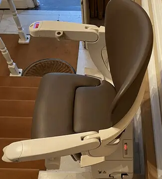 Brown swivel-seat straight stairlift on indoor wooden stairs in Shidler.