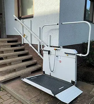 White outdoor wheelchair platform lift installed on stone steps in Hatfield, MA.